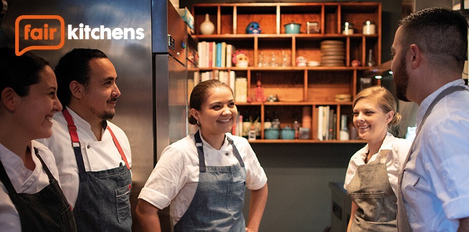 Group of male and female Chefs standing in kitchen, smiling from the positive work environment created through #FairKitchens.